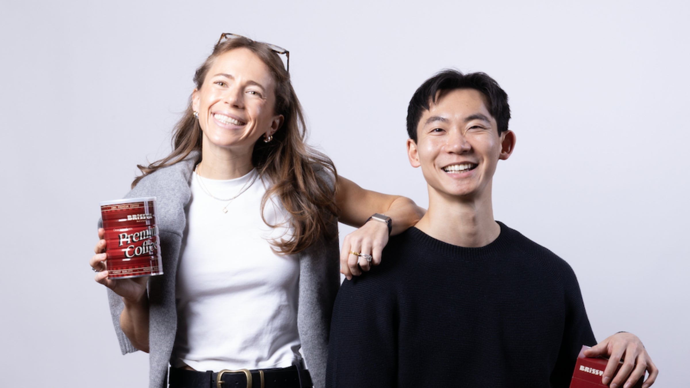 Picture of 2 people holding Brissta tin can and packaging against a plain background