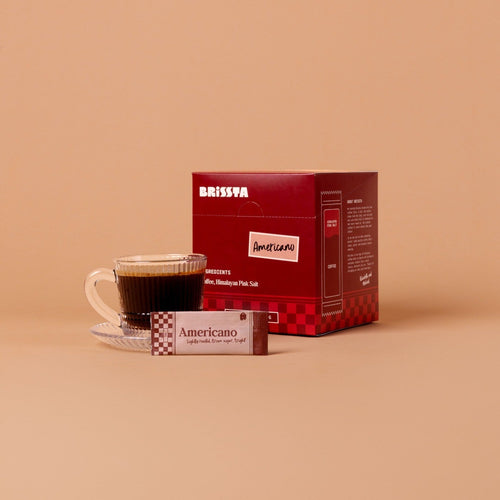 Mug of Brissta Americano with packaging in background on a beige background
