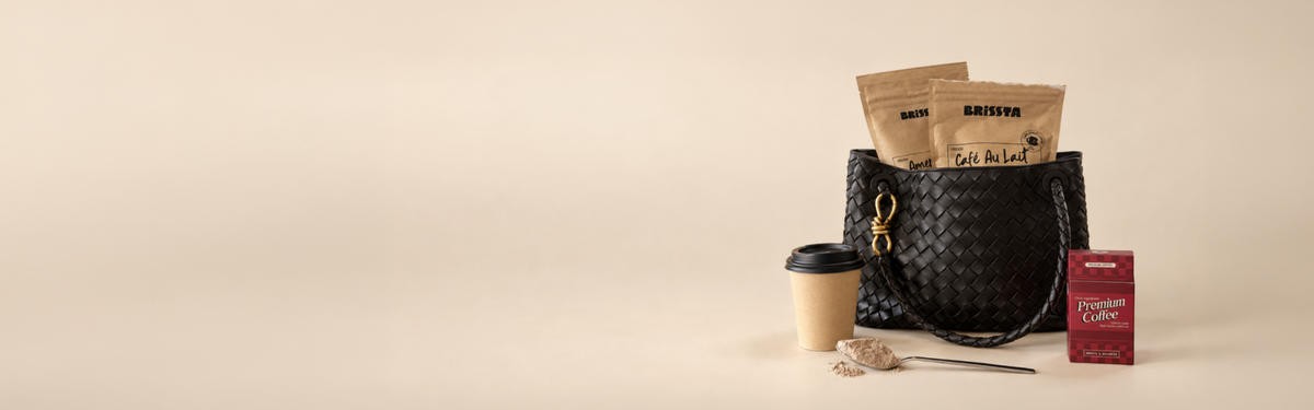 Brissta Café Au Lait and Americano bags in a woven tote, with a to-go cup, a spoonful of coffee powder and a Premium Coffee box